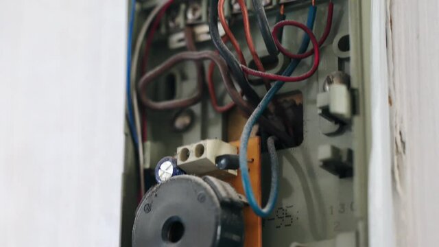 Close-up of an old security system at home, open intercom box with defective wires and dusted handset. Vintage broken surveillance security sustem inside the house, internal home protection