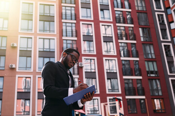 A young African-American engineer draws on a construction site.