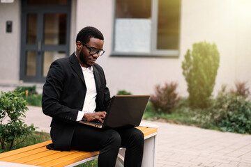 Handsome young african american man working on laptop, sitting o