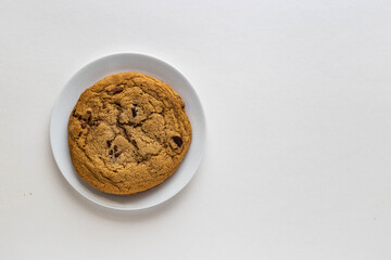 Chocolate chip cookie in white porcelain plate on white background