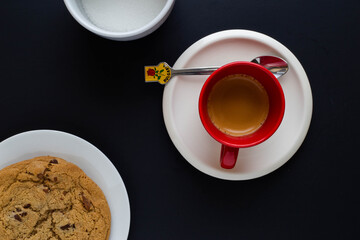 Espresso coffee with Bulgaria themed spoon, sugar and chocolate chip cookie on black background