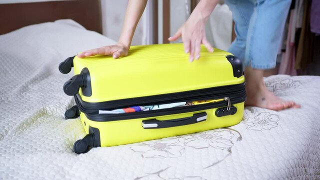 travel suitcase, young woman tries to close her case with things sits on top and closes the zipper on her travel bag for travel trip during her summer vacation to resort