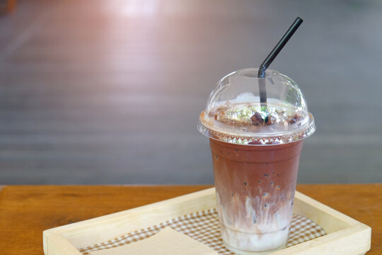 Iced milk chocolate drink served in plastic glass on wood table