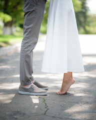 feet of two lovers, bride and groom on their wedding day. The guy in the shoes, the girl is barefoot. Romantic Outdoor with summer season nature on background.