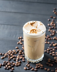 A glass of iced coffee on black wooden table. Selective focus.