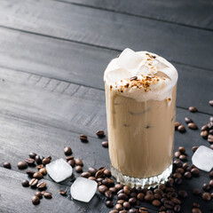 A glass of iced coffee on black wooden table. Selective focus.