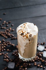 A glass of iced coffee on black wooden table. Selective focus.