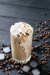 A glass of iced coffee on black wooden table. Selective focus.
