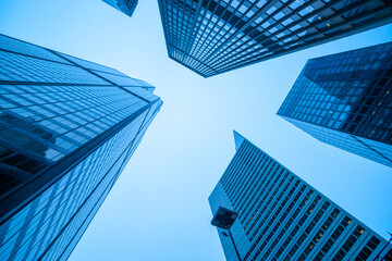 Fototapeta na wymiar Converging high-rise commercial office buildings in blue hues.