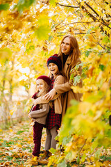 mother with daughters in autumn park under yellow maples. happy family.
