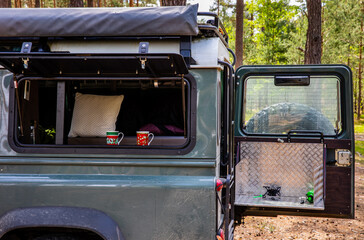 Open side window and back door in off-road tourist car. Preparing hot beverage tea in forest. Cooking stove and cups.