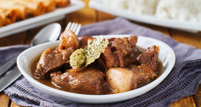 filipino pork adobo in bowl with rice in background