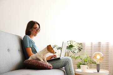 Portrait of young beautiful hipster woman working at home with her adorable jack russell terrier...