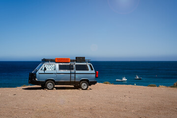 Fototapeta na wymiar Camper van parked on the beach in front of the blue sea during holidays