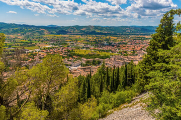Obraz premium The cathedral city of Gubbio, Italy visible above the Cypress trees on the slopes of Mount Ingino in summer