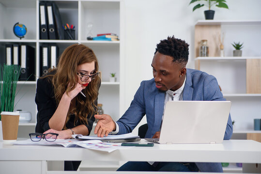 Successful young mixed race work team analysing financial report during their work under joint project at the boardroom table. Business and financial concept. - Powered by Adobe