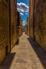 A view down a narrow alleyway at siesta time in the city of Gubbio, Italy in summer
