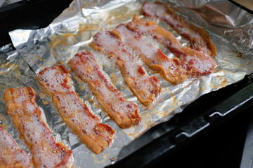 Freshly baked hot crispy bacon on the baking tray just from the oven