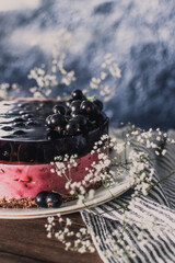 Cheesecake mousse cake with black currant. Delicious cake with berries on a wooden table.