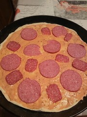 Pizza in the pan is not yet sprinkled with cheese, the process of cooking pizza.