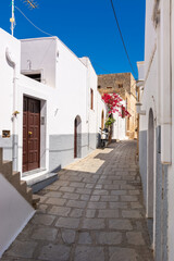 Greek narrow street with white houses on Rhodes island. Lindos village, Dodecanese, Greece.