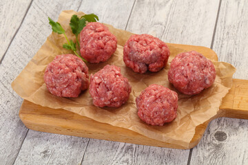 Raw meatball over wooden background