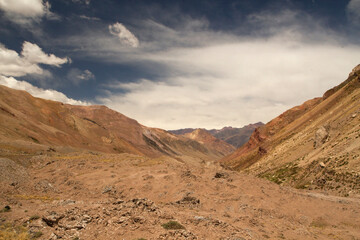 Desert landscape. Geology. Panorama view of the arid valley and red mountains under a dramatic blue sky. 