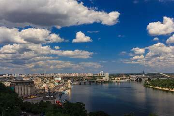 Summer cityscape. Big river in the city under the sky with clouds. The Dnieper River in Kyiv. The historical center of Kyiv.