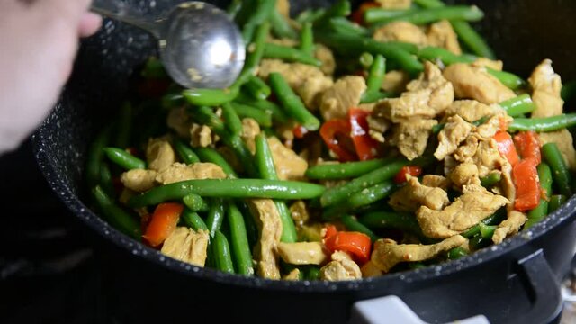 Sprinkling fresh green bean pods over a delicious chicken tikka masala with Indian spices