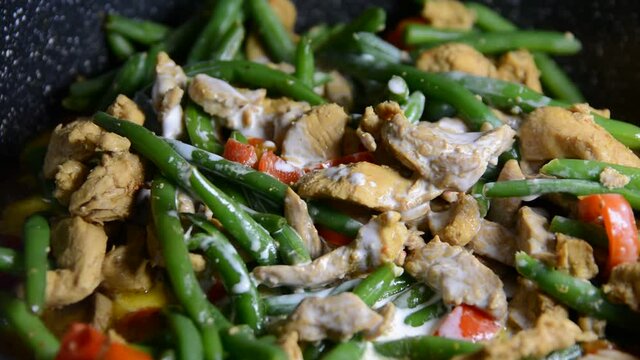Sprinkling fresh green bean pods over a delicious chicken tikka masala with Indian spices