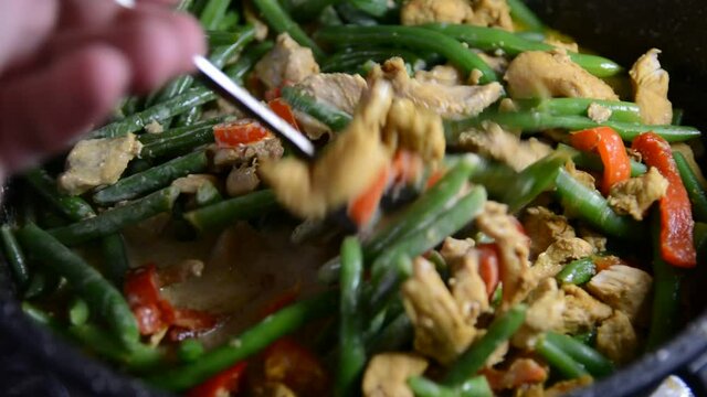 Sprinkling fresh green bean pods over a delicious chicken tikka masala with Indian spices