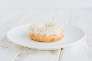 Close-up view of donut on a small white plate with white background. Fresh sweet colorful homemade vanilla donuts on vintage background for birthday or party, with free space for text