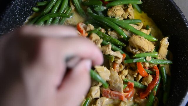 Sprinkling fresh green bean pods over a delicious chicken tikka masala with Indian spices