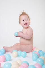 Fototapeta na wymiar 11 month old baby girl on a white background in the studio playing with toy balls