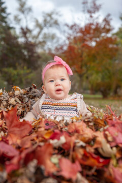 Baby playing outdoors in the fall leaves posing for pictures