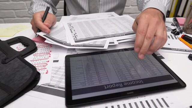 Business analysis and accounting concept - businessman working with document, spreadsheet, using calculator, tablet pc. Office desk closeup. 

