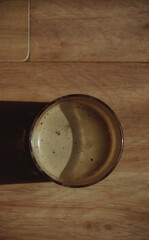 Glass with coffee with milk with white foam on a wooden background.