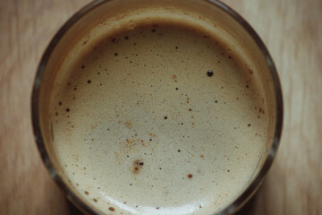 Close-up of a glass of coffee with milk, with white foam.