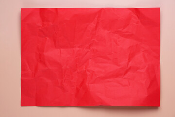 Close up of red crumpled empty sheet of paper on pink background.