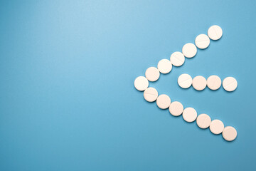 Close up of many white pills on blue background.