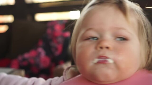 Close up of one year old chubby baby girl fed from spoon open mouth very wide funny