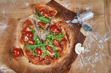 Delicious, juicy and tasty rustic homemade vegetarian pizza on wooden board with cherry tomato, rucola, mozzarella basil and mushrooms. 