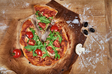 Delicious, juicy and tasty rustic homemade vegetarian pizza on wooden board with cherry tomato, rucola, mozzarella basil and mushrooms. 
