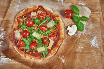 Delicious, juicy and tasty rustic homemade vegetarian pizza on wooden board with cherry tomato, rucola, mozzarella basil and mushrooms. 