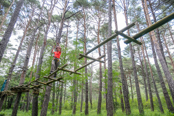 woman crossing a tibetan bridge in an adventure park in a pine forest