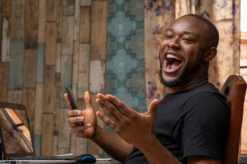 excited young black man holding his mobile phone