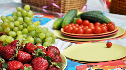 picnic with basket, fruits and vegetables on lawn in summer day