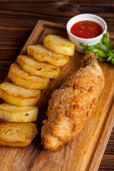fried chicken with potatoes on a wooden background