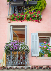 Fototapeta na wymiar Charming blooming flower covered balcony and window of upstairs apartments in Europe