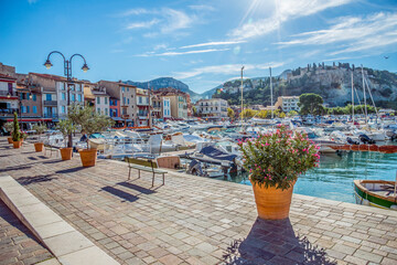 Peaceful sunny boardwalk by harbor with tourism and fishing boats coastal town in France￼
